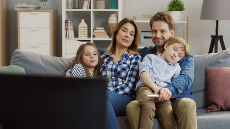 Familie-Mit-Kindern,-Die-Auf-Dem-Sofa-Im-Wohnzimmer-Sitzen-Und-Fernsehen