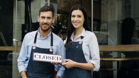 Attractive-Smiled-Woman-And-Man,-Workers-Of-The-Restaurant,-Standing-On-The-Street-At-The-Door-Looking-At-Each-Other-And-Then-To-The-Camera