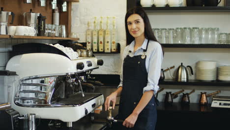 Porträtaufnahme-Der-Hübschen-Lächelnden-Kellnerin,-Die-Kaffee-Auf-Der-Kaffeemaschine-Zubereitet-Und-In-Die-Kamera-Schaut