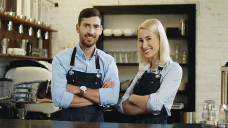 Portrait-Shot-Of-The-Attractive-Waiter-And-Waitress-Standing-And-Looking-At-Each-Other,-Then-Turning-And-Smiling-To-The-Camera