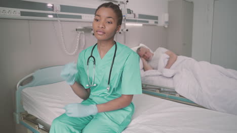 A-Beautiful-Young-American-Nurse-Sitting-On-The-Edge-Of-A-Hospital-Bed-Thinking