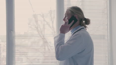 A-Young-Doctor-With-Long,-Blond-Hair,-Makes-A-Mobile-Phone-Call