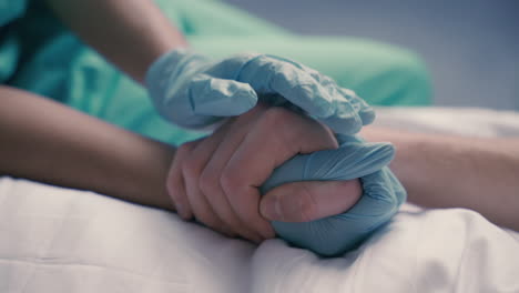 Detail-Of-A-Nurse's-Hands-Grasping-And-Comforting-The-Hands-Of-A-Sick-Patient-On-Hospital-Bed-1