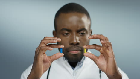 Close-Up-Of-The-Young-Doctor-Holding-Two-Pills-In-Hands-Yellow-And-Blue-And-Looking-At-Them-1