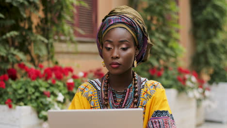 Close-Up-Of-The-Pretty-Young-Woman-In-The-Traditional-Outfit-And-With-Scarf-On-The-Head-Wotking-At-The-Laptop-Computer-In-The-Beautiful-Cortyard