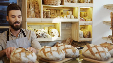 The-Male-Vendor-In-The-Bakery-Shop-Bringing-Just-Baked-Bread-To-The-Counter