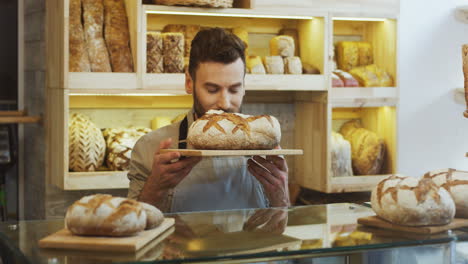 Young-Attractive-Man-Bread-Seller-Putting-Fresh-Bread-On-The-Counter-In-The-Morning