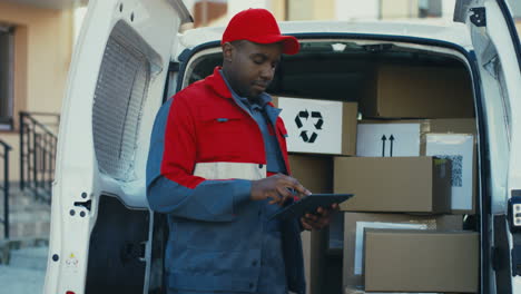 Deliveryman-In-Red-Costume-And-Cap-Checking-The-Mail-Boxes-With-Tablet-Computer-In-Hands