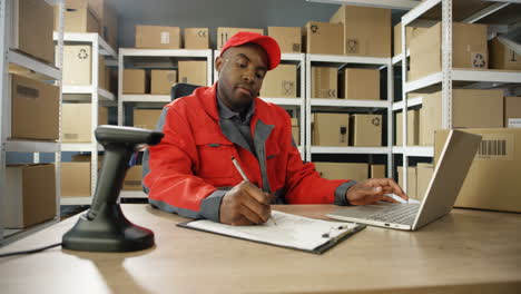 Young-Man-In-Uniform-Sitting-At-Table-And-Typing-On-Latop-Computer-While-Registering-Mail-Box-In-Post-Office