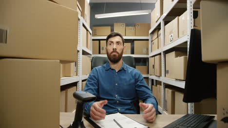 Man-Sitting-At-Table-With-Many-Carton-Boxes-As-Having-A-Lot-Of-Work-And-Parcels-In-Delivery-Store
