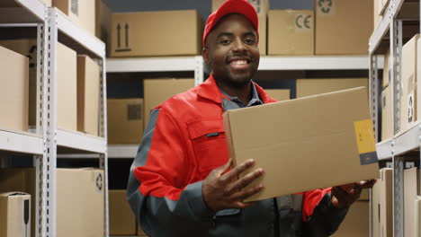 Young-Postman-In-Uniform-Taking-Out-Carton-Box-From-Shelf-In-Post-Office-Store-Of-Shipping