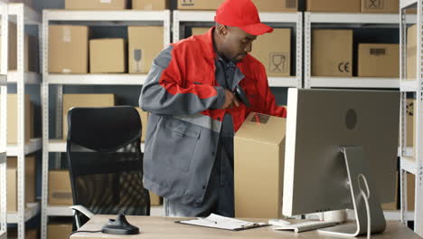 Postbote-In-Uniform,-Der-Am-Computer-Im-Postgeschäft-Mit-Paketen-Arbeitet