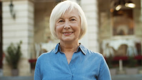 Close-Up-Of-Joyful-Pretty-Gray-Haired-Old-Woman-In-Blue-Jeans-Shirt-Smiling-Outdoors
