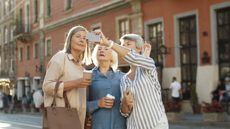 Tres-Hermosas-Ancianas-Sonriendo-Mientras-Toman-Una-Foto-Selfie-Con-Una-Cámara-De-Teléfono-Inteligente-En-La-Calle-En-El-Centro-De-La-Ciudad