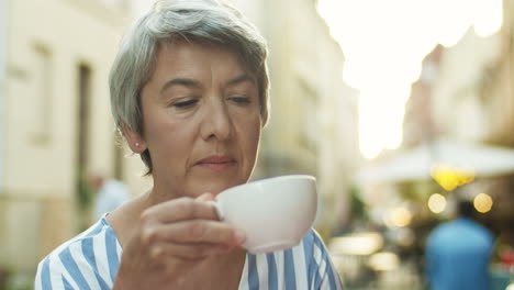 Cerca-De-Una-Anciana-Seria-Y-Pensativa-Con-Cabello-Gris-Disparado-Bebiendo-Café-Y-Pensando-Al-Aire-Libre