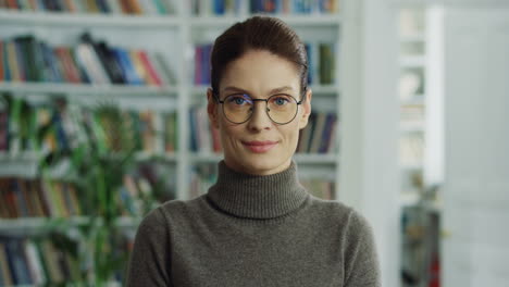 Portrait-Of-The-Attractive-Woman-In-The-Glasses-Looking-At-The-Side-And-Then-Smiling-Nice-To-The-Camera-In-The-Room-With-Books