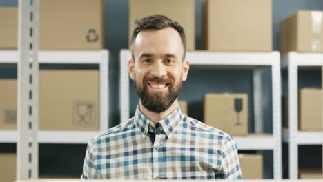 Close-Up-Of-Good-Looking-Postman-Taking-Carton-Box-With-Bar-Code-From-Shelf-And-Smiling-To-Camera-In-Post-Office-Store