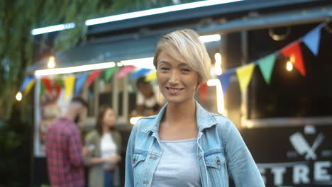 Close-Up-Of-Pretty-Blond-Young-Woman-With-Short-Hair-Smiling-Cheerfully-To-Camera-Outdoor