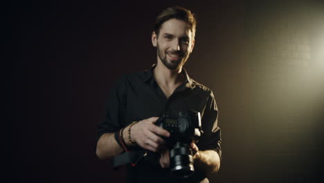 Camera-Zooming-In-And-Taking-In-Focus-Attractive-Male-Photographer-Who-Setting-His-Photocamera-And-Then-Smiling-Cheerfully