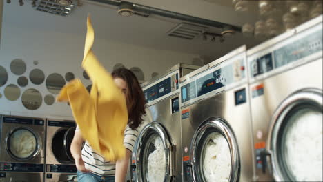 Cheerful-Young-Beautiful-Woman-Having-Fun-And-Laughing-As-Throwing-Clothes-From-Basket-At-Laundry-Service