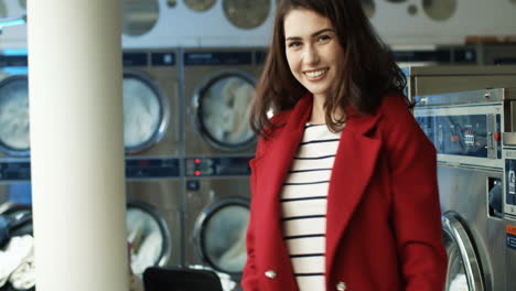 Beautiful-Cheerful-Woman-In-Stylish-Outfit-Having-Fun-And-Dancing-In-Laundry-Service-Room-While-Machines-Washing-On-Background-1