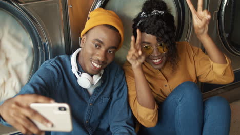 Fröhliches-Paar-Lächelt-In-Die-Smartphone-Kamera,-Während-Es-Im-Wäscheservice-Ein-Selfie-Foto-Macht