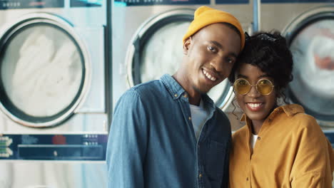 Portrait-Of-Happy-Cheerful-Couple-In-Love-Hugging-And-Smiling-To-Camera-In-Laundry-Service