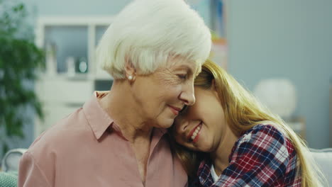 Portrait-Of-The-Pretty-And-Cute-Teen-Girl-And-Her-Good-Looking-And-Gray-Haired-Grandmother-Looking-At-Each-Other,-Smiling-And-Hugging