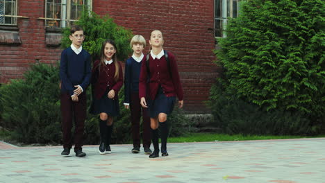 Cute-Happy-Schoolchildren-Running-Near-Their-School-With-Their-Bags-Over-Backs-After-Classes
