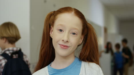 Portrait-Of-The-Cute-Pretty-Red-Haired-Teen-Girl-With-Two-Tails-Smiling-Cheerfully-To-The-Camera-At-The-School-Coridor-During-A-Break