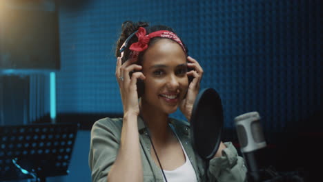Close-Up-Of-The-Young-Atractive-And-Happy-Young-Girl-Singer-Taking-Off-Headphones-And-Smiling-To-The-Camera-After-Finishing-Recording-A-Song-In-The-Sound-Studio