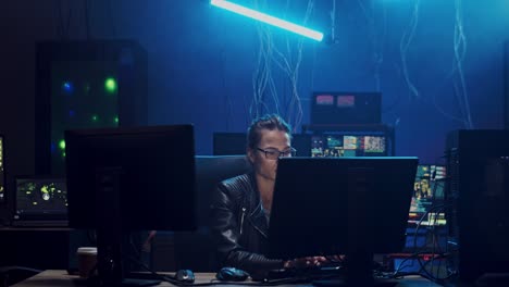 Young-Woman-In-Glasses-Sitting-And-Working-At-The-Computer-In-The-Dark-Room-With-Technologies,-Hacking-The-System-And-Laundring-Data