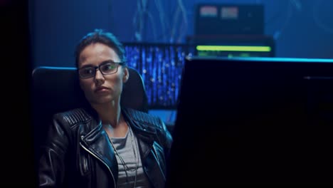Camera-Zoming-In-On-The-Young-Software-Developer-Woman-In-Glasses-Sitting-In-Front-Of-The-Computer-Screen-And-Resting