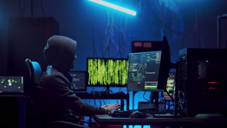 Seitenansicht-Des-Anonymen-Männlichen-Cyberkriminellen-In-Der-Kapuze,-Der-Nachts-Im-Dunkeln-Daten-Hackt-Und-Viren-Am-Computer-Kodiert