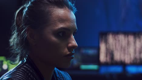 Close-Up-Of-The-Beautiful-Young-Female-Hacker-Looking-At-The-Screen-Of-Computer-While-Working-At-Night-In-The-Dark