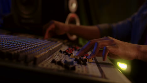 Close-Up-Of-The-Male-Hands-Working-At-The-Sound-Board-Or-Mixer-At-The-Dark-Studio-While-Man-Mastering-A-Song