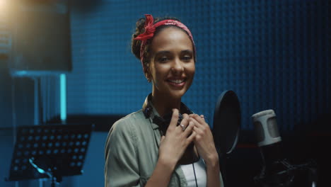 Close-Up-Of-The-Pretty-Young-Female-Singer-In-Stylish-Look-Smiling-Cheerfully-To-The-Camera-At-The-Microphone-At-Therecording-Sound-Studio