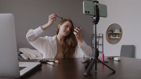 Young-Cute-Vlogger-Girl-Testing-An-Eye-Mascara-In-Front-Of-Her-Smartphone-Camera