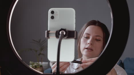 Close-Up-Of-A-Pretty-Vlogger-Female-Making-A-Video-Review-Of-A-Make-Up-Brush-Talking-Directly-To-Her-Smartphone's-Camera
