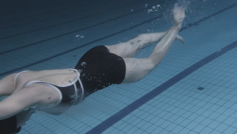 Unterwasseraufnahme-Einer-Jungen-Schwimmerin,-Die-In-Den-Pool-Springt-Und-Hineintaucht