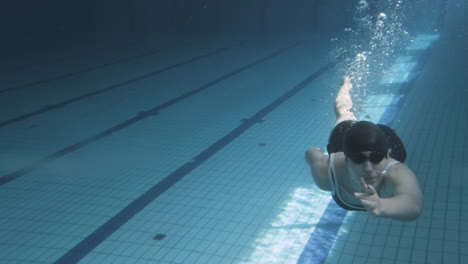 Unterwasseraufnahme-Einer-Jungen-Schwimmerin,-Die-Durch-Den-Boden-Eines-Schwimmbeckens-Taucht