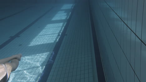 Unterwasseraufnahme-Einer-Jungen-Schwimmerin,-Die-In-Einem-Hallenbad-Taucht