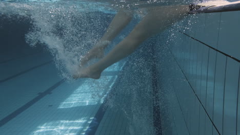 Unterwasser-Nahaufnahme-Der-Beine-Einer-Jungen-Frau,-Die-Am-Rand-Eines-Schwimmbeckens-Trainieren