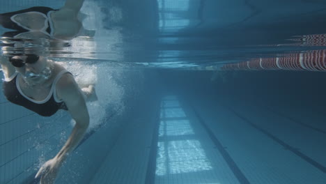 Unterwasseraufnahme-Einer-Jungen-Frau,-Die-Im-Pool-In-Richtung-Kamera-Schwimmt