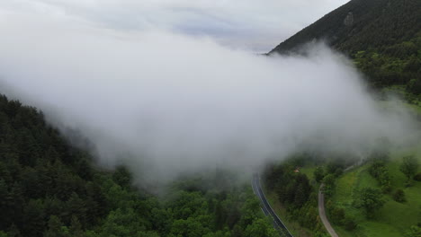 Shot-From-The-Air-Coming-Out-Of-A-Large-Cloud-Located-Over-A-Forest-In-The-Pyrenees