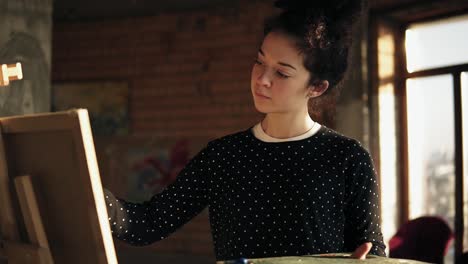 Fully-Concentrated-Sophisticated-Female-Artist-In-Her-20's-Is-Drawing-Picture-On-Easel