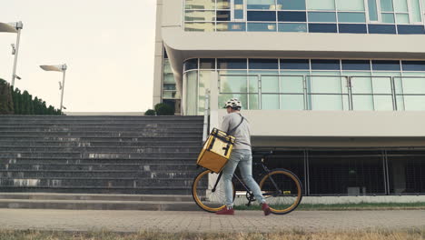 Food-Delivery-Guy-Wearing-Thermal-Backpack-Leaves-His-Bike-On-The-Ground-And-Walks-Up-The-Stairs-To-Make-A-Delivery