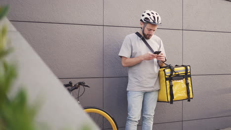 Food-Delivery-Man-With-A-Thermal-Backpack-Consults-An-Order-On-His-Smartphone