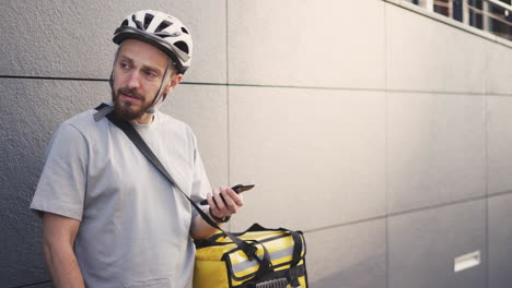 Confused-Food-Delivery-Guy-With-A-Thermal-Backpack-Consults-An-Address-On-His-Smartphone-Because-He-Is-Lost