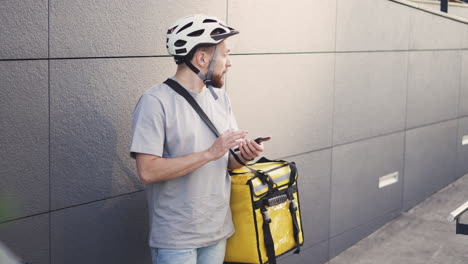 Lost-Food-Delivery-Guy-With-A-Thermal-Backpack-Consults-An-Address-On-His-Smartphone-Because-He-Doesn'T-Know-Where-The-Deliver-Is